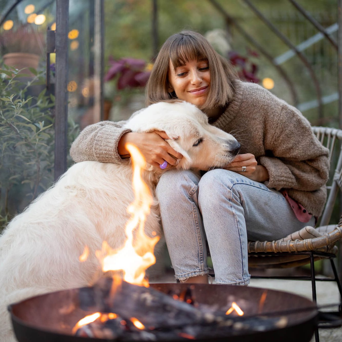 woman-with-dog-by-the-fire-in-garden-2022-10-04-22-06-11-utc